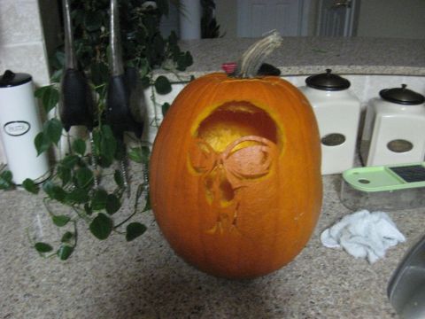 1978 Ford Bronco - A pumpkin carved with a skull face sits on a kitchen counter next to canisters and plants.