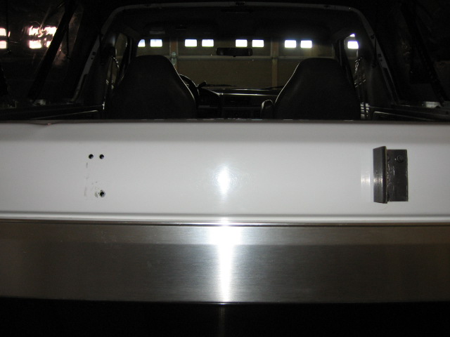 White tailgate interior of a Ford Bronco with drilled holes and black latch bracket
