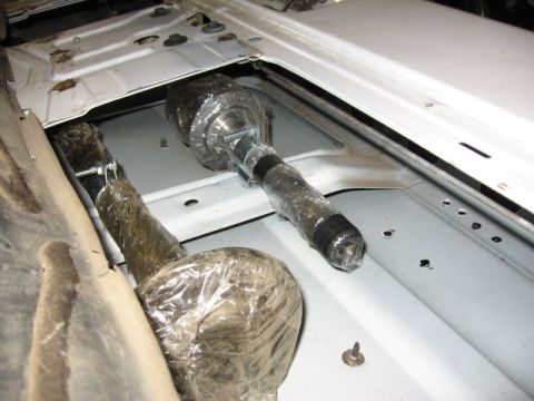 1995 Ford Bronco - Two tie rod ends are visible, wrapped in protective plastic, inside a vehicle's chassis.