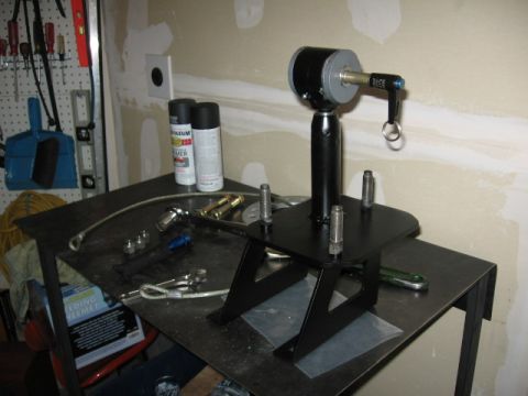 1995 Ford Bronco - A black tire carrier part is shown on a workbench with various tools and spray paint cans nearby.