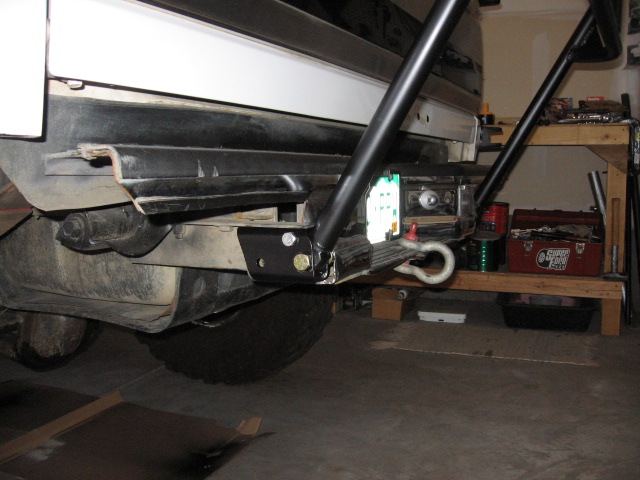 Black frame-mounted recovery tow hook bracket under a vehicle in a garage