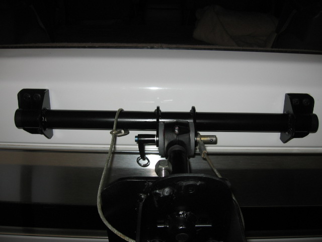 Black horizontal roller bar on brackets over white surface with cable