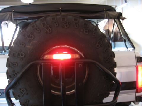 1995 Ford Bronco - The rear of a 1995 Ford Bronco is shown, a spare tire mounted on a carrier with a visible brake light.