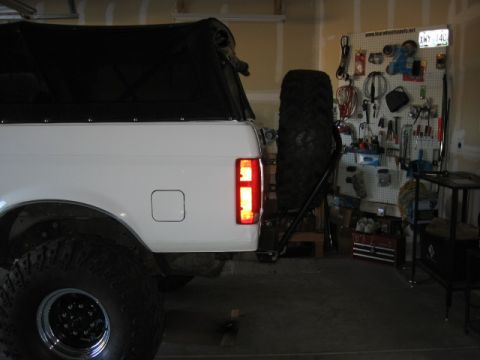 1995 Ford Bronco - The rear of a 1995 Ford Bronco is shown with a spare tire carrier and a pegboard with tools in the background.