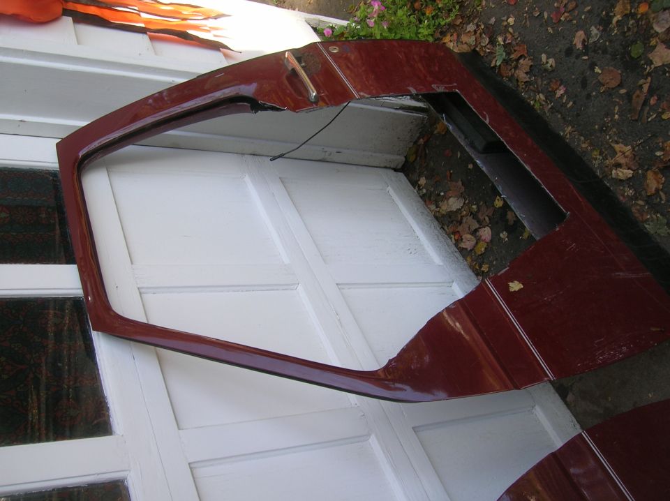 Maroon car door with chrome handle, lying on a white garage door