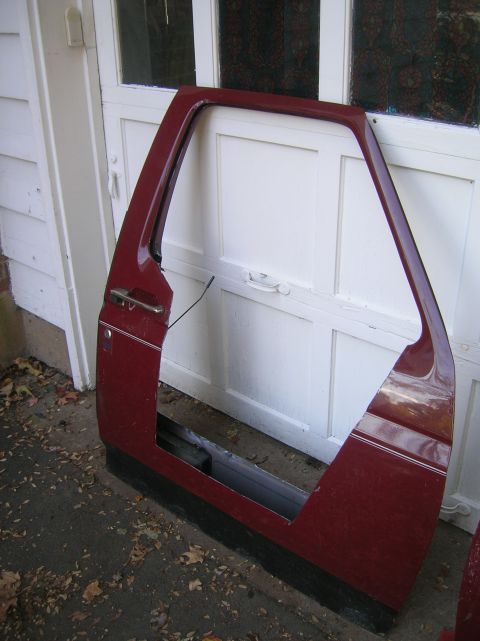 1996 Ford Bronco - A single maroon car door, likely from an SUV, is shown leaning against a garage door.
