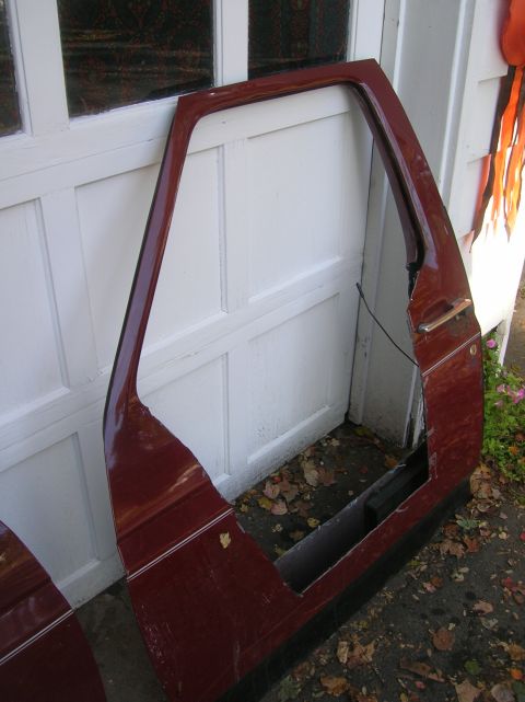 1996 Ford Bronco - A pair of maroon half doors, likely for a Ford Bronco, are shown leaning against a white garage door.