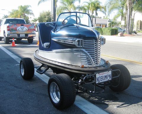 1968 Ford Mustang - A unique custom vehicle with a boat-inspired body is parked on the street next to a pickup truck.