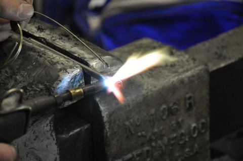 1996 Ford Bronco - A torch heats a metal wire secured in a vise, with visible text on the vise itself.