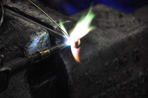 1996 Ford Bronco - A torch is used to heat a small metal component clamped in a vise.