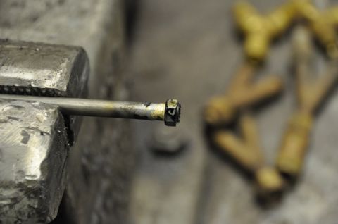 1996 Ford Bronco - A metal rod is secured in a vise, with other brass-colored parts out of focus in the background.