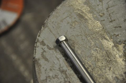 1996 Ford Bronco - A close-up view of a metal bolt resting on a textured, circular surface.