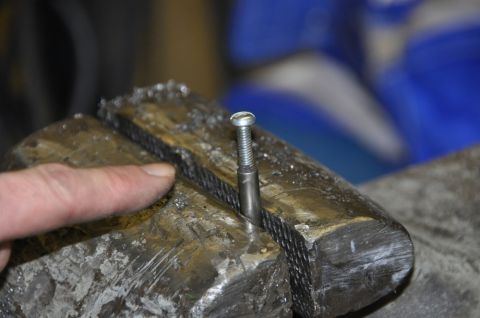 1996 Ford Bronco - A screw is secured in a metal vise, ready for work.