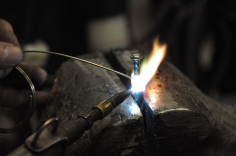 1996 Ford Bronco - A close-up shows a screw being heated by a torch while a wire is held nearby.