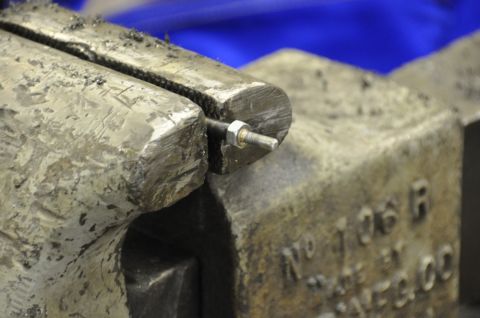 1996 Ford Bronco - A bolt with a nut is secured in a heavy-duty vise, ready for work.