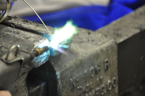 1996 Ford Bronco - A torch is used to heat a bolt secured in a vise, with visible text on the vise itself.