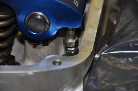 1996 Ford Bronco - Close-up view of a blue roller rocker arm assembly connected to a valve spring within an engine.