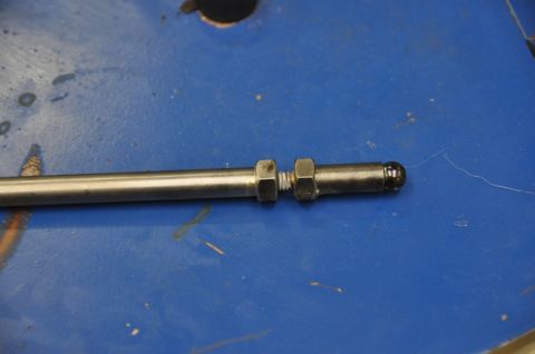 1996 Ford Bronco - A close-up view of a metal rod with adjustable nuts, likely a component for a larger assembly.