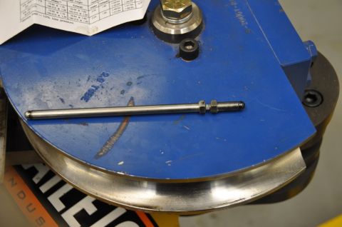 1996 Ford Bronco - A metal rod rests on a blue tube bending tool, with a chart visible in the background.