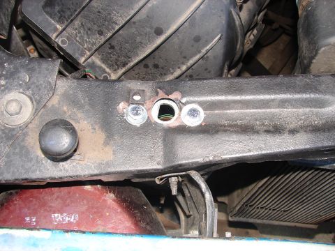 1973 Ford Ranchero - Detail of engine bay components, including bolts and wiring, with some red and blue painted parts visible below.