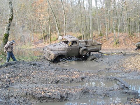 1990 Ford Bronco - A vintage pickup truck is stuck deep in mud during an off-road event.