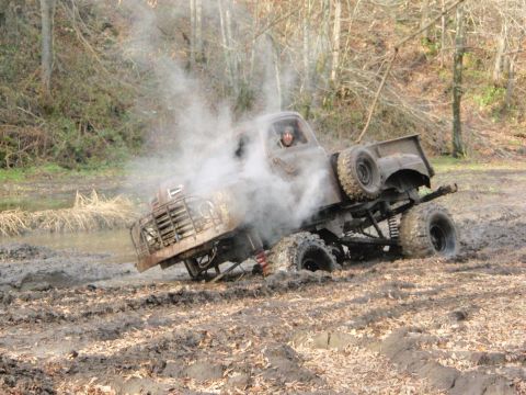 1990 Ford Bronco - This heavily modified pickup truck is stuck deep in the mud, with smoke coming from the engine area.