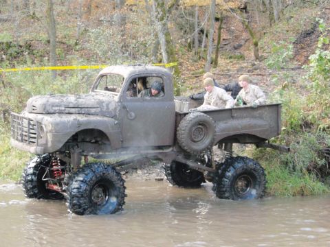 1990 Ford Bronco - This heavily modified pickup truck navigates through a muddy stream with several passengers in tow.