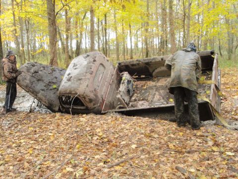 1990 Ford Bronco - Two people stand near an overturned pickup truck in a forest during autumn.