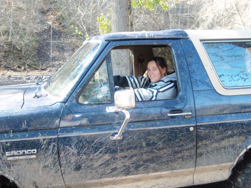Mud-covered 1990 Ford Bronco side view with driver