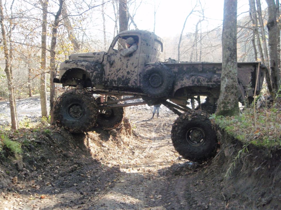 Muddy old pickup truck with huge tires driving off-road