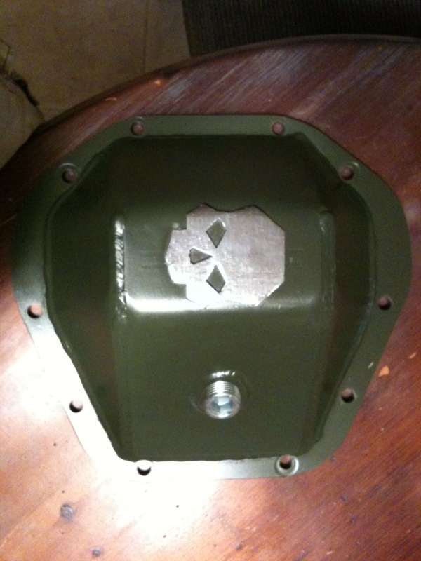 Green differential cover with a metal plate cut into a skull shape inside. Has a threaded plug at the bottom