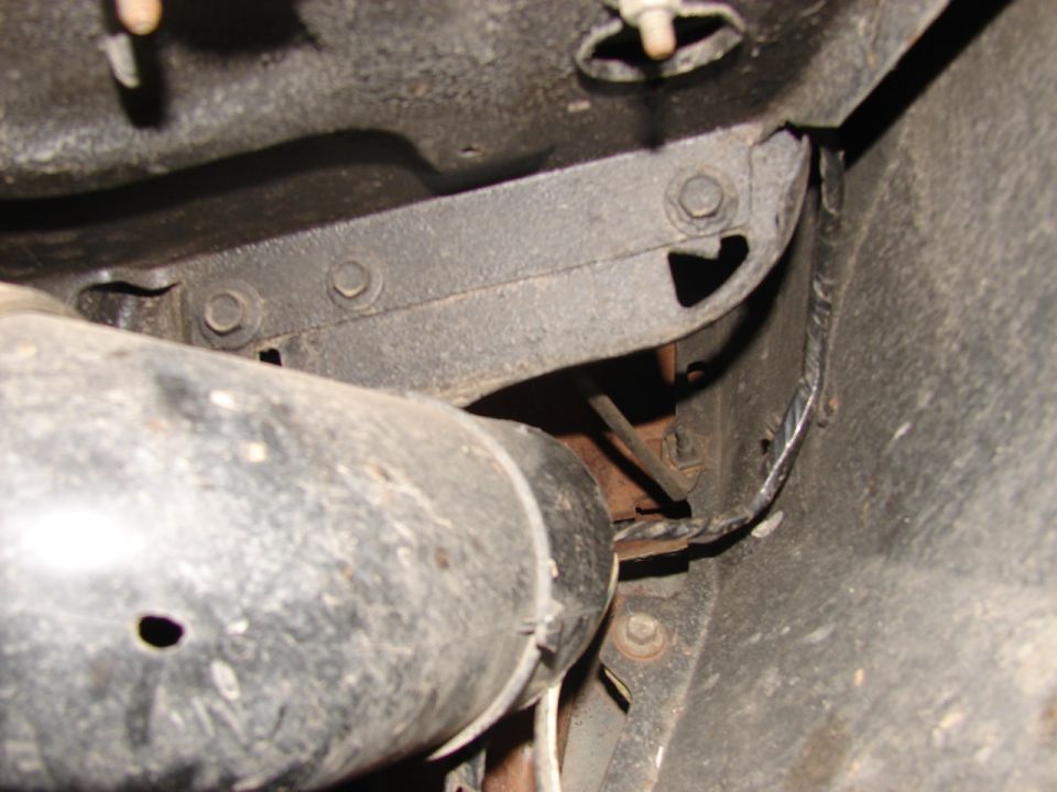 Close-up of vehicle undercarriage showing exhaust pipe and metal frame brackets