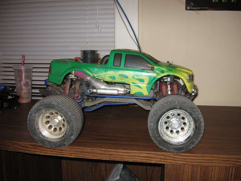 Green remote control monster truck with flame decals, large tires, and visible engine components