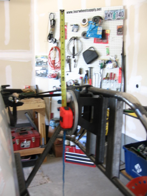 1995 Ford Bronco - A metal tire carrier frame is measured in a garage. Tools and supplies are visible on a pegboard in the background.
