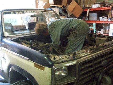 1982 Ford Bronco - Mechanic works on the engine of a 1982 Ford Bronco, possibly during an engine swap.