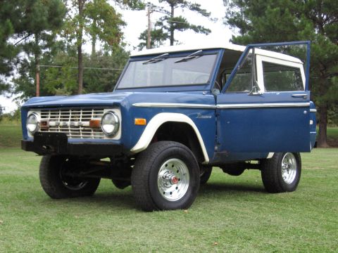 1967 Ford Mustang - This blue 1974 Ford Bronco features a white hardtop and an open driver's door, viewed from a three-quarter front angle.