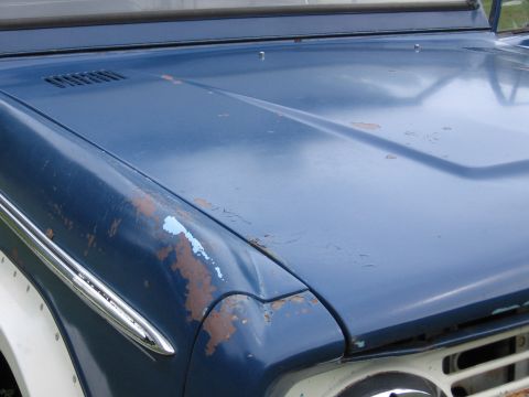 1967 Ford Mustang - Close-up of a blue vehicle's hood with significant rust damage and peeling paint.