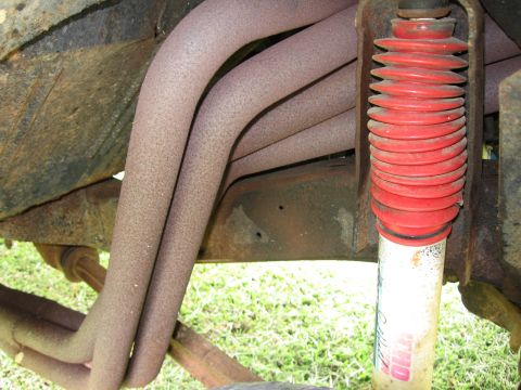 1967 Ford Mustang - Vehicle underside shows exhaust manifold pipes and a red shock absorber boot.