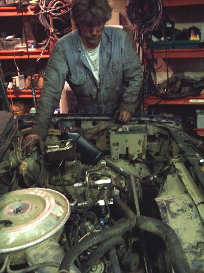 1982 Ford Bronco - Mechanic works on the engine of a 1982 Ford Bronco in a garage setting.