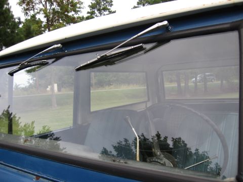 1967 Ford Mustang - View through the windshield of a vintage blue truck's interior, with wipers visible.