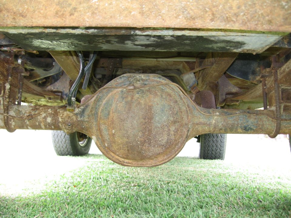Underside view of a rusty rear axle and leaf springs on a vehicle