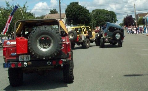 1982 Ford Bronco - Several off-road vehicles participate in a parade, including a red vehicle with a spare tire mounted on the rear.