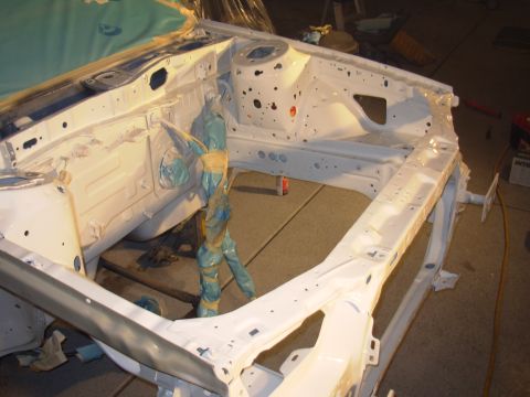 1995 Ford Taurus - The bare frame of a vehicle's engine bay, covered in white primer and protective blue wrapping.