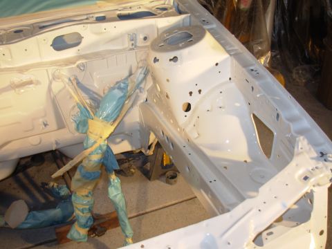 1995 Ford Taurus - The white painted car frame shows areas of rust and is partially covered with protective tape.