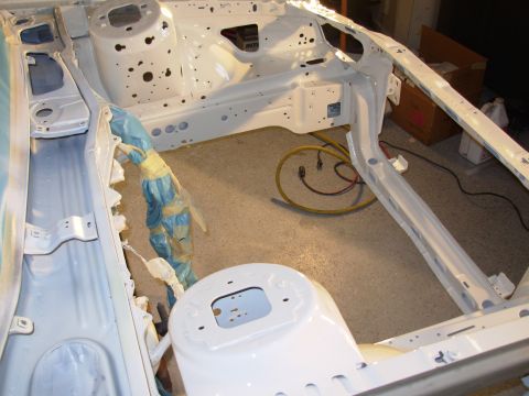 1995 Ford Taurus - The bare frame of a car is shown, possibly undergoing restoration or repair, with wiring protected by blue tape.