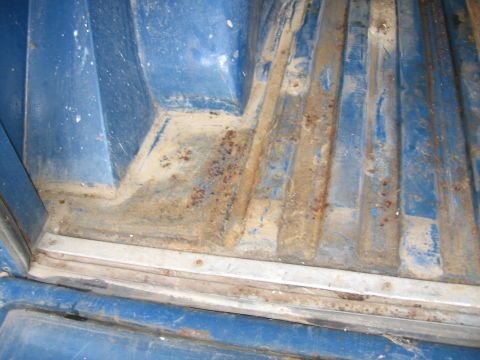 1967 Ford Mustang - The ribbed interior of a blue truck bed shows significant rust and dirt accumulation.