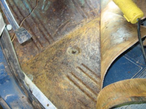 1967 Ford Mustang - Interior view of a rusted floor pan with carpet pulled back, revealing a pedal.
