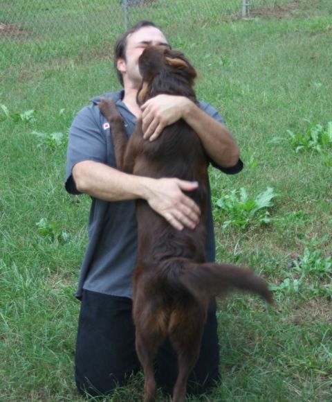 1976 Ford Ranchero - A man embraces a brown dog in a grassy outdoor area.