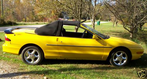 Yellow Ford Probe convertible conversion parked on grass with top down
