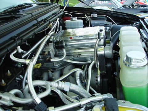 2001 Ford Excursion - Close-up of an engine bay a chrome supercharger and various hoses, with another vehicle visible in the background.